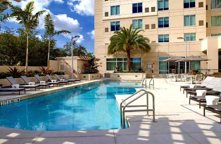 durante o dia, espreguiçadeiras em frente a piscina em um dos hotéis baratos em miami