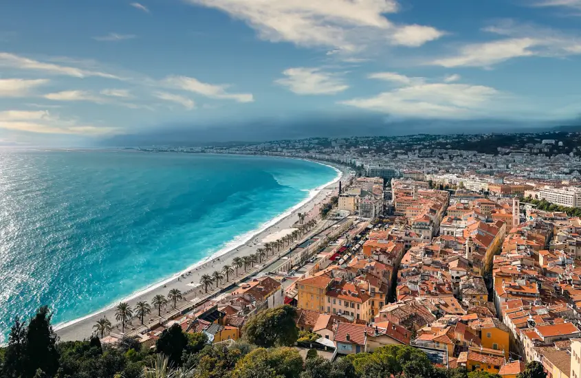 Em um dia ensolarado, paisagem de Nice com praia de um lado e cidade do outro