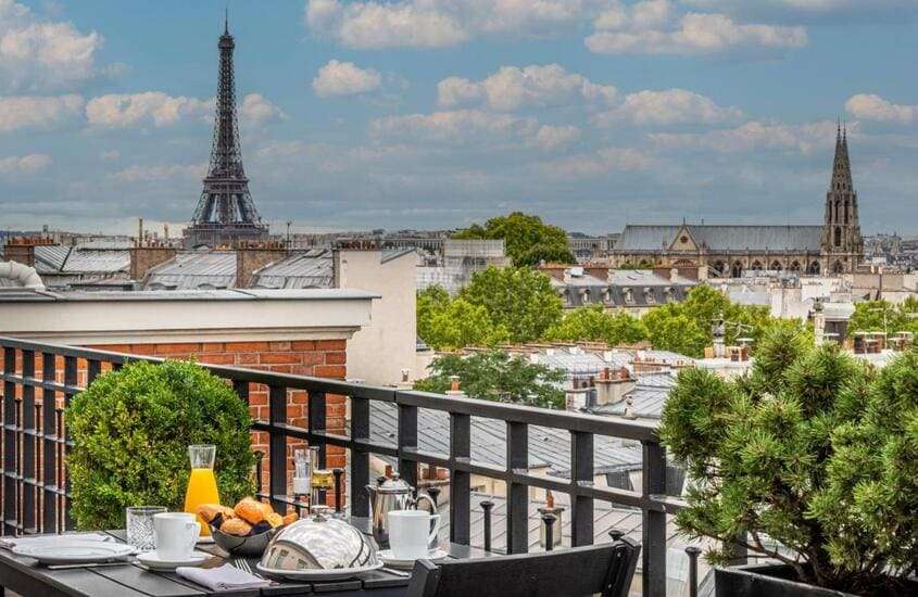 durante o dia, croissants, frutas e suco servido em mesa em varanda de hotel em Paris com vista da Torre Eiffel