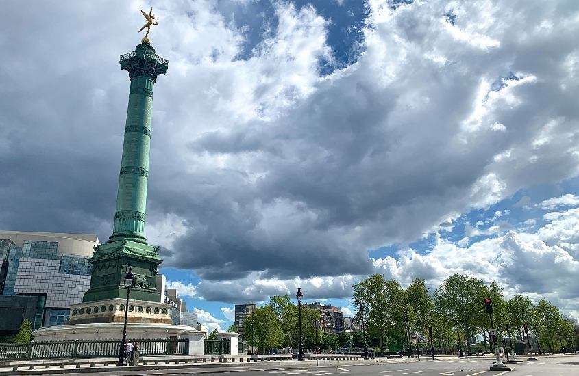 durante dia nublado, monumento verde, em rua arborizada de Bastille , um lugar onde ficar em paris