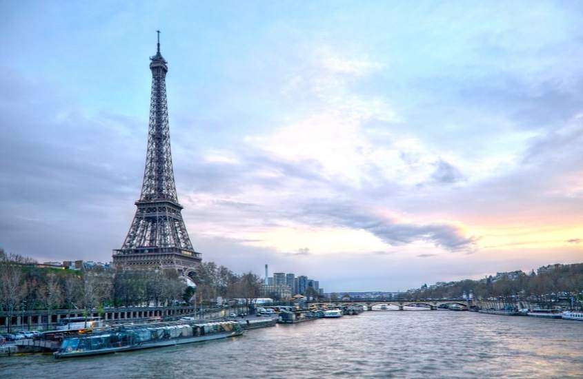 durante o dia, barcos atracados em rio com vista para a Torre Eiffel