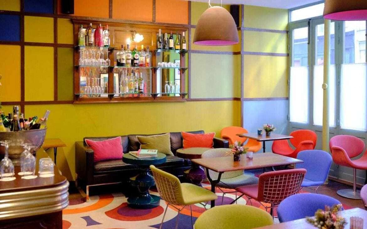mesas e cadeiras coloridas em lounge de um dos melhores hotéis em Paris