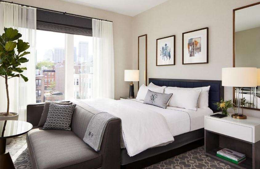 durante o dia, sofá cinza e cama de casal em ampla suite com vista para a cidade em um dos melhores hoteis em boston
