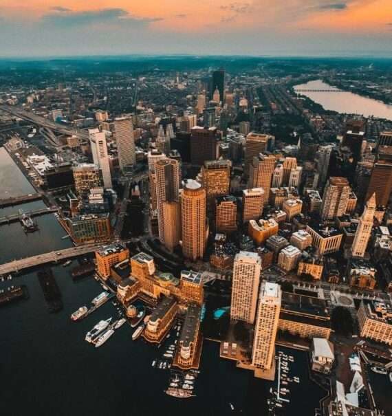 durante entardecer, vista aérea de arranha-céus e prédios em frente ao mar em boston eua