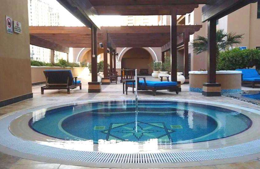 espreguiçadeiras azuis em frente a piscina redonda em área de lazer ar livre de um hotel em doha