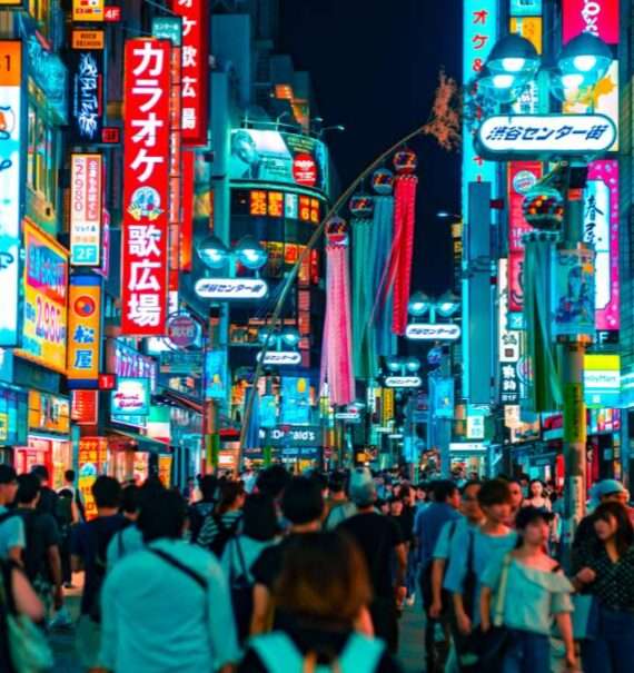 durante a noite, pessoas caminhando em rua cercada de letreiros iluminados em ruas de Tokyo Japão