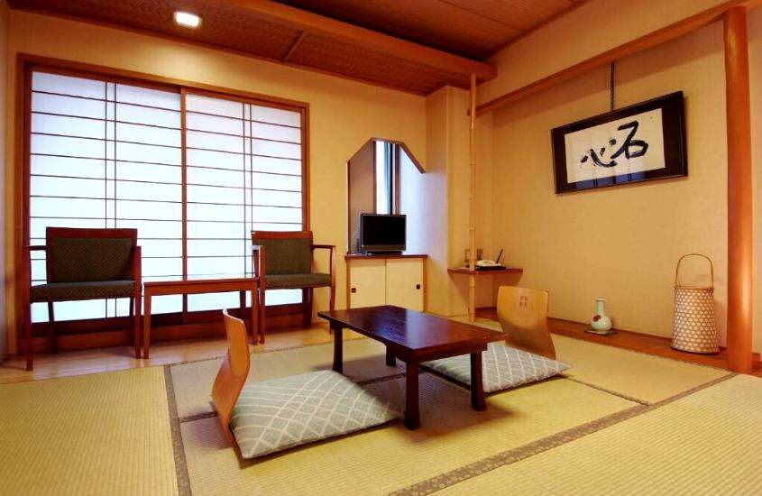 cadeiras, mesa de centro de madeira e almofadas em sala de estar de ryokan em Tokyo Japão
