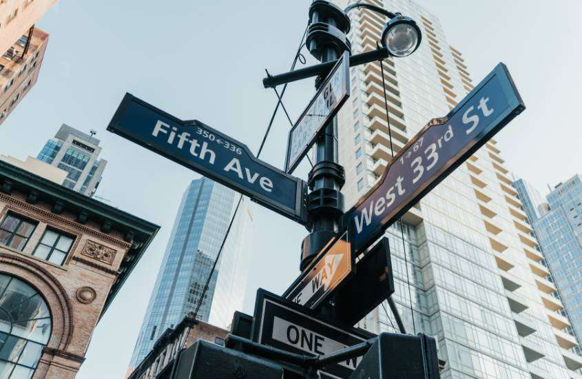 durante o dia, placa azul e branca escrito 'fifth ave' e 'west 33rd st' em rua de nova york eua