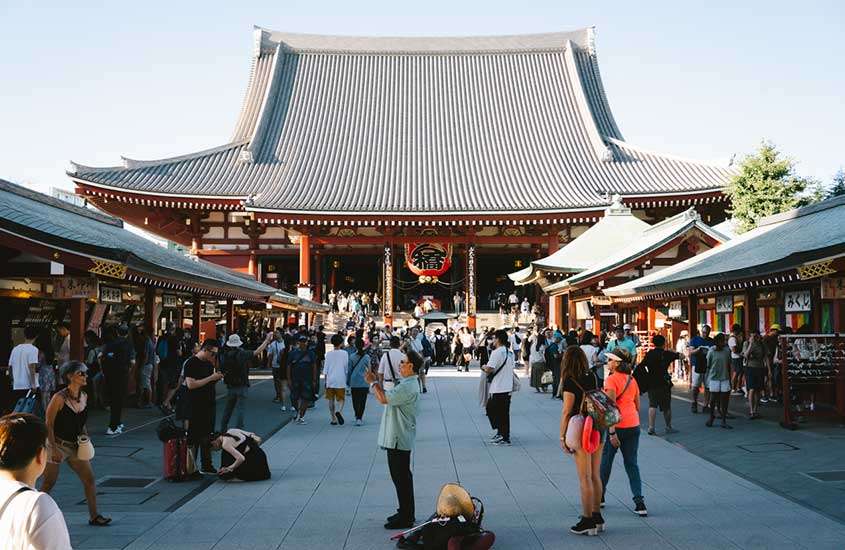 Em um dia de sol, templo Senjo-ji com pessoas ao redor