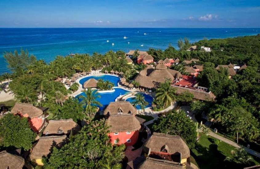durante o dia, vista aérea de árvores ao redor de piscina, em complexo de um dos resorts em Cozumel a beira mar