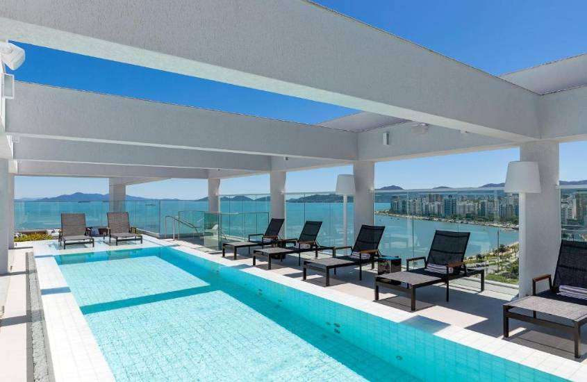 durante dia ensolarado, espreguiçadeiras em frente a piscina em terraço com vista para o mar