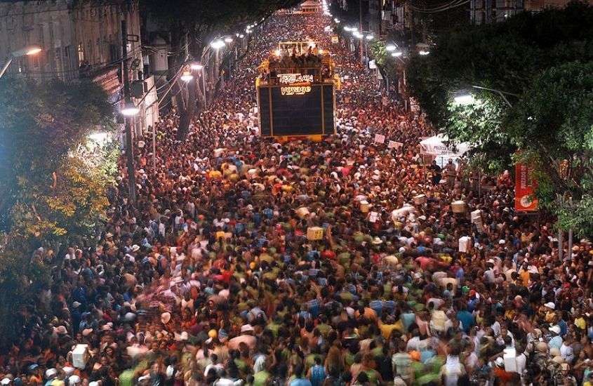 durante a noite, vista aérea de diversas pessoas pulando carnaval em salvador ao redor de trio elétrico