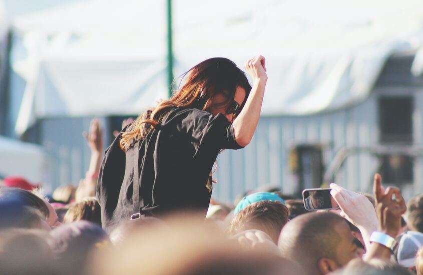 mulher no ombo de outra pessoa, em meio a multidão de festival de música