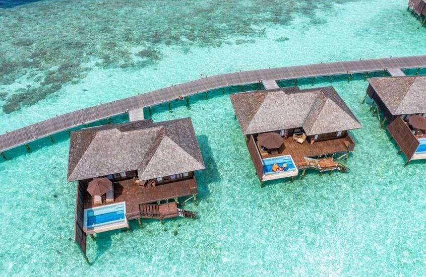durante dia ensolarado, vista aérea de bangalôs sobre as águas em um dos resorts nas Maldivas