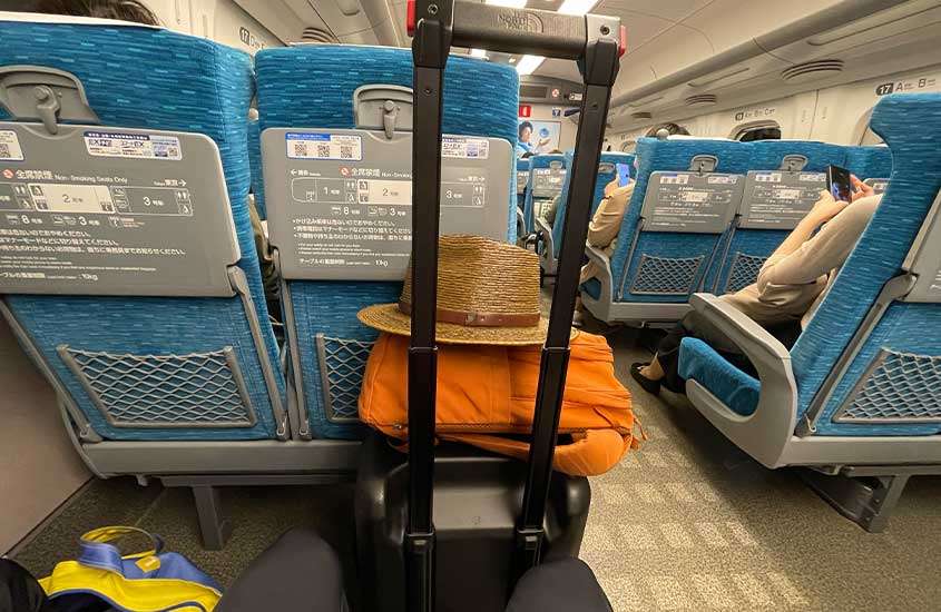 Interior do trem bala no Japão com malas e bancos azuis