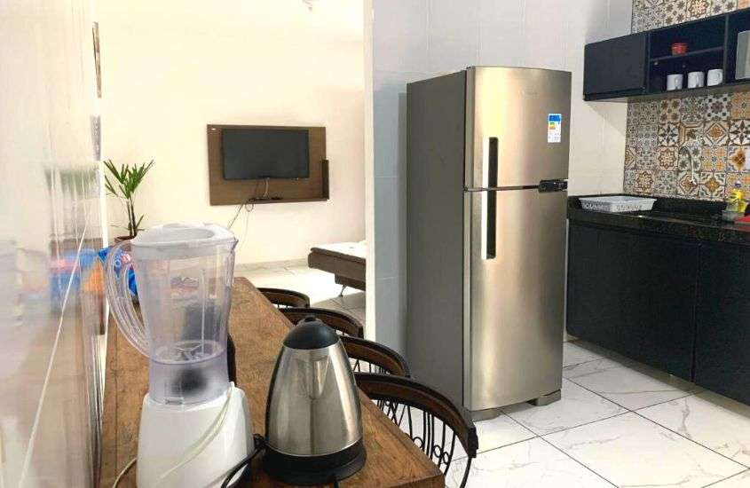 liquidificador e cafeteira em cima de mesa de madeira, geladeira cinza e armário preto em cozinha de um apartamento em ouro preto