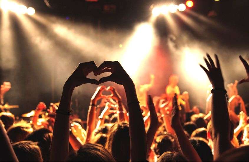 pessoas em frente a palco, fazendo símbolo de coração com as mãos, durante festa de carnaval em são paulo