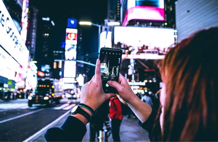 durante a noite, pessoa fotografando com o celular prédio em nova york