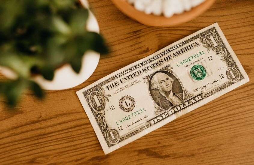 nota de 1 dólar em cima de mesa de madeira