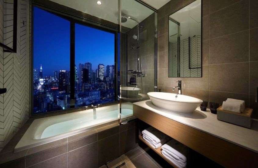 durante a noite, banheira de hidromassagem em banheiro com vista para cidade em suíte de um dos melhores hotéis em tokyo