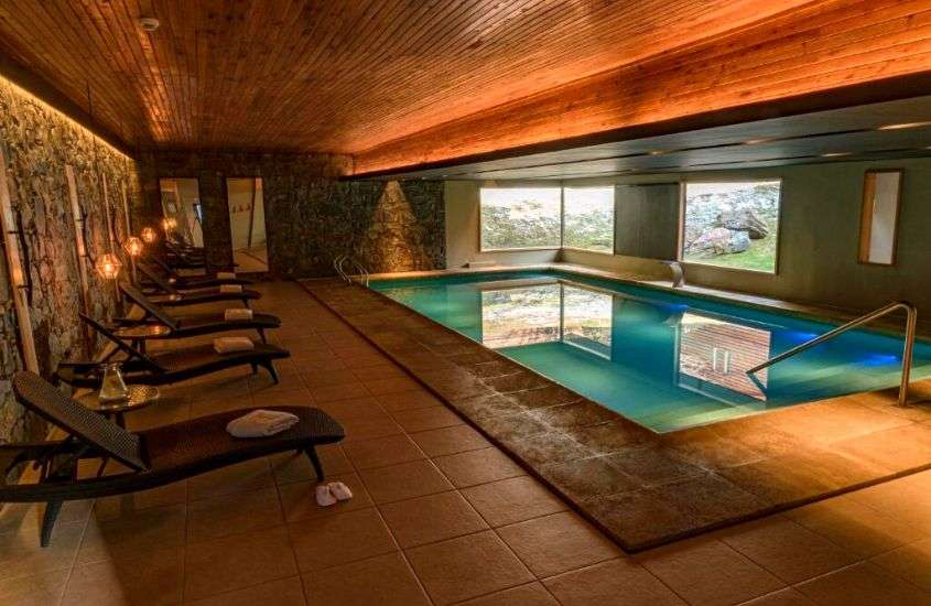 espreguiçadeiras em frente a piscina em área de lazer coberta de um dos melhores hoteis em ushuaia