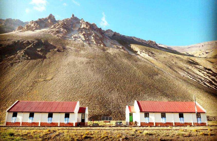 durante o dia, casas brancas, com telhados vermelhos, em frente a grande montanha