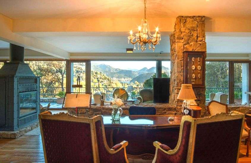 durante o dia, lareira e mesa de jantar em sala de estar de hotel com amplas janelas com vista para as montanhas