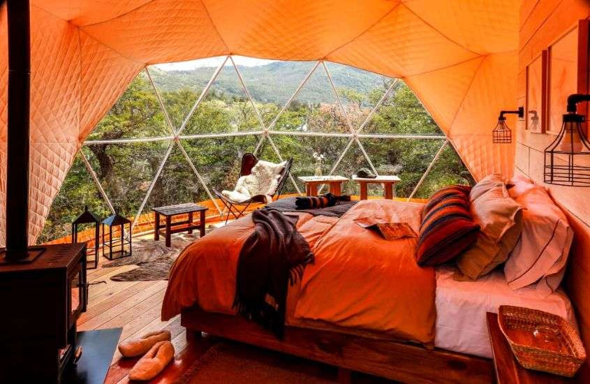 durante o dia, cama de casal e cadeiras em domo com vista para as montanhas