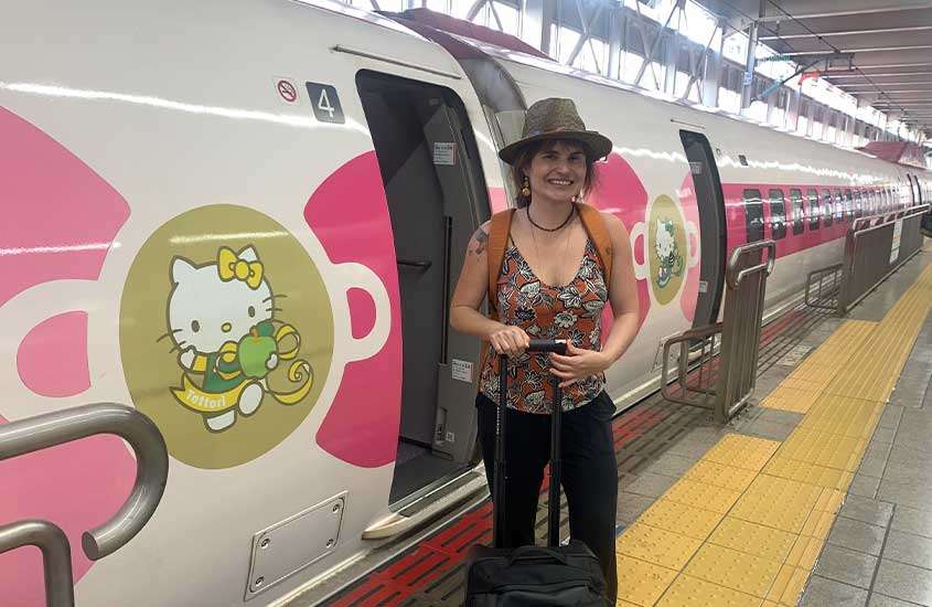 Bárbara Rocha Alcantelado em frente ao trem com decorações da Hello Kitty