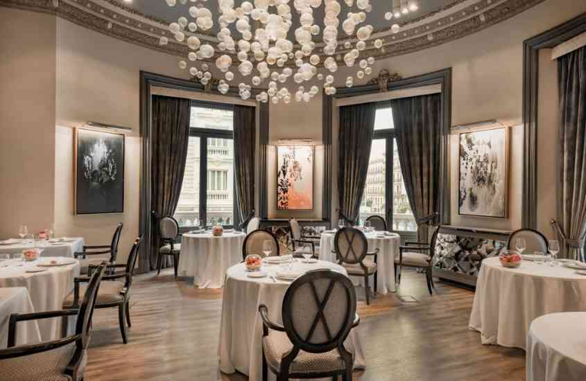 cadeiras cinzas ao redor de mesas redondas, forradas com toalha branca, em restaurante de um dos melhores hotéis em madri