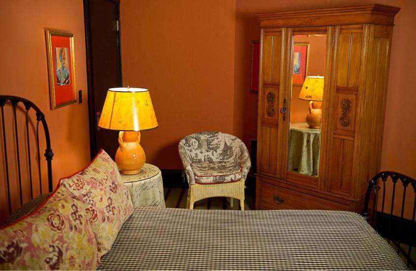 cama de casal, poltrona e armário de madeira em suite com paredes laranjas