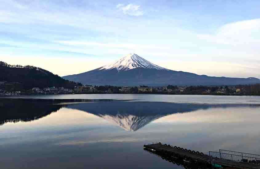 durante o dia, reflexo de pico de vulcão coberto por neve em lago
