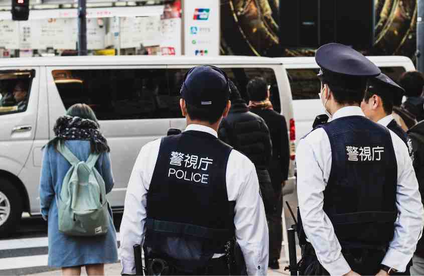 durante o dia, duas pessoas de costas, com coletes pretos, onde há escrito ''police''