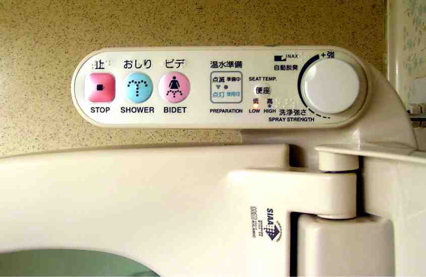 privada high-tech da cultura japonesa, com botões coloridos, onde há escrito 'stop', 'shower' e 'bidet'