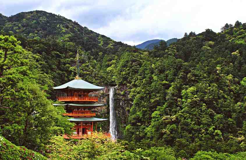 durante o dia, templo de madeira com telhado verde, em meio a montanhas