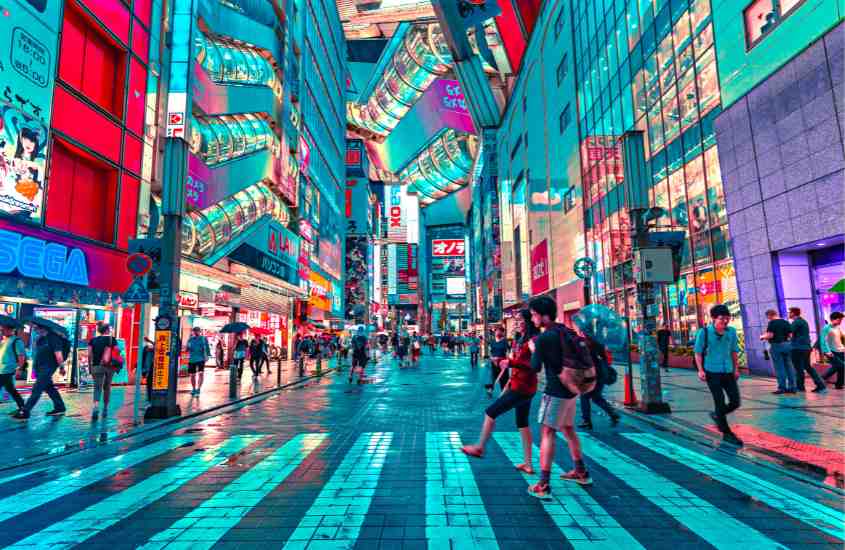 pessoas caminhando em rua cercada por prédios com letreiros coloridos em tokyo, que de acordo com curiosidade do japão é a maior cidade do mundo