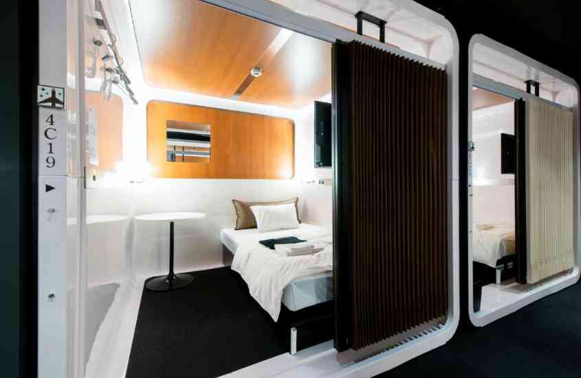 pequena mesa redonda e cama de solteiro em cabine de hotel cápsula no japão