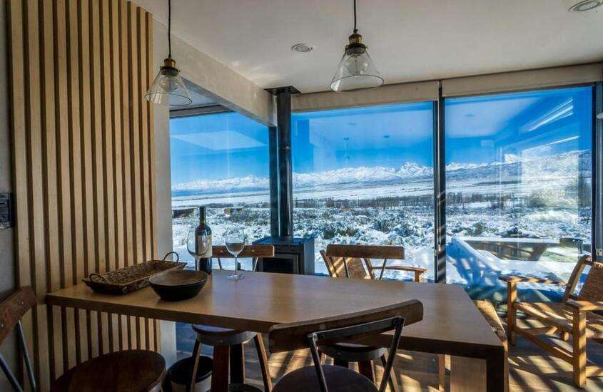 durante o dia, garrafa de vinho em cima de mesa de madeira em suíte de hotel com vista para montanhas nevadas