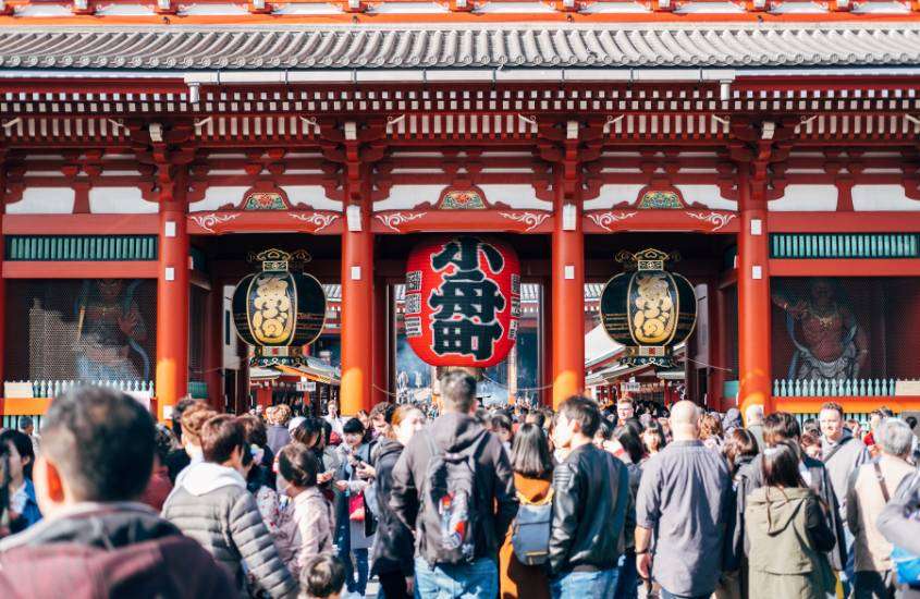durante o dia, diversas pessoas caminhando em área externa de templo japonês