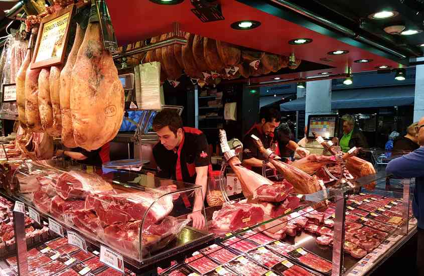 pessoas escolhendo carne em barraca de mercado