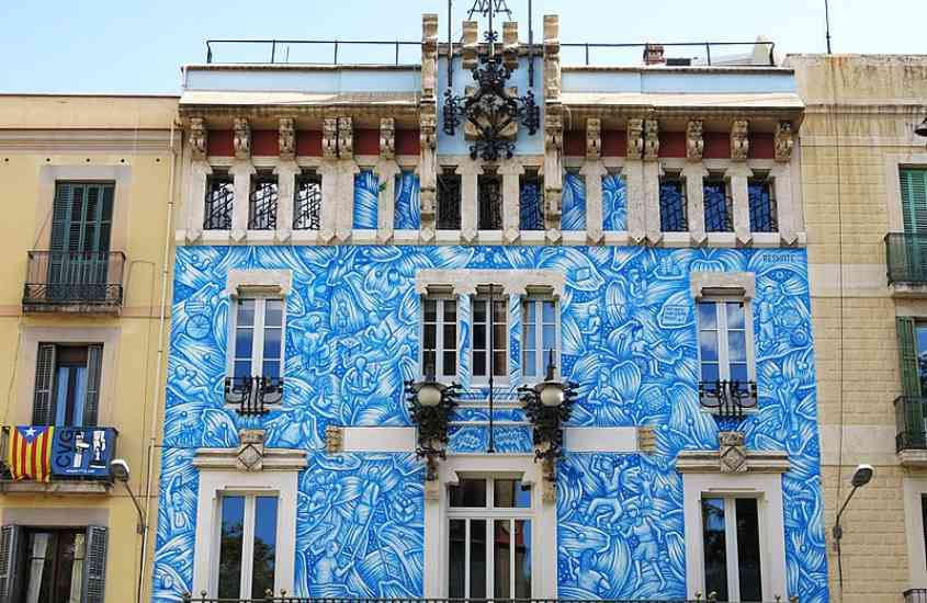 durante o dia, prédio branco com desenhos azuis em grácia, atração para quem busca o que fazer em Barcelona