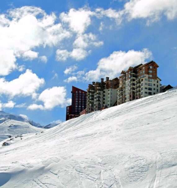 durante o dia, prédio vermelho e branco em topo de montanha coberta de neve em Valle Nevado