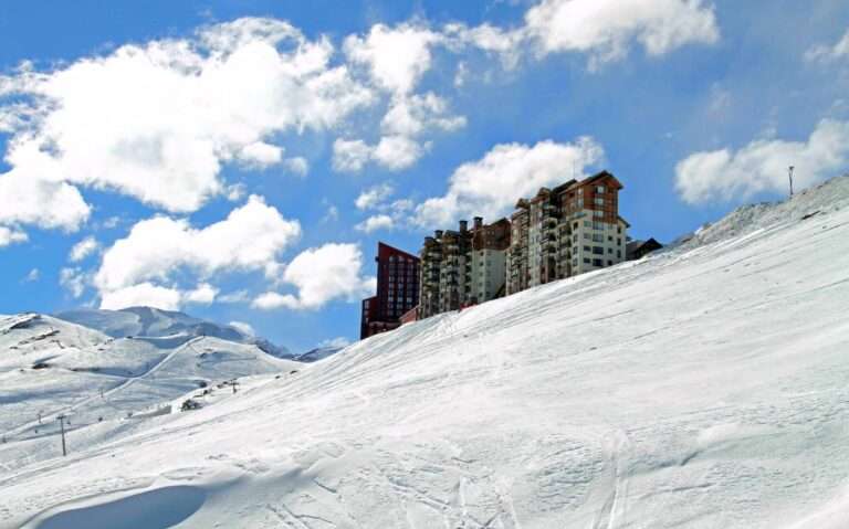 durante o dia, prédio vermelho e branco em topo de montanha coberta de neve em Valle Nevado