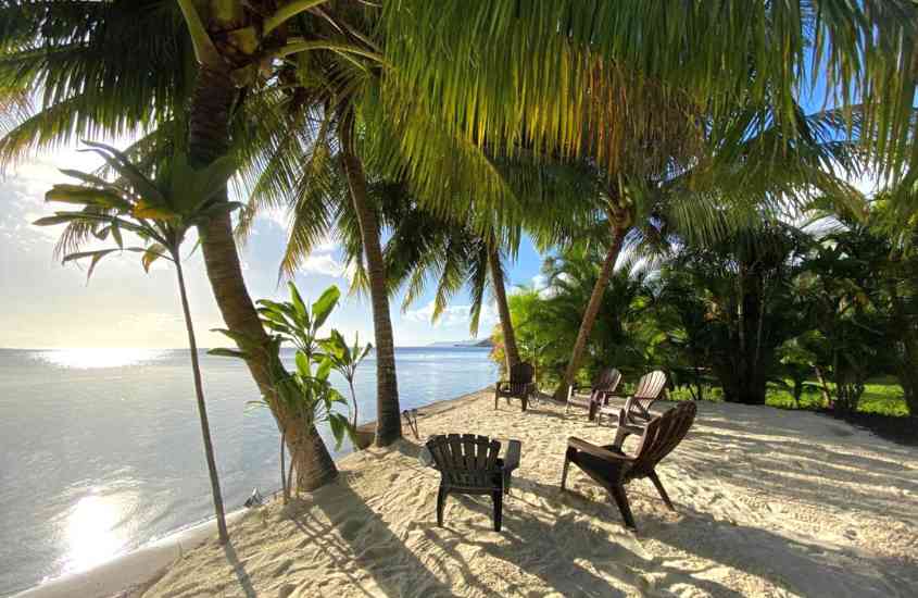 durante dia ensolarado, cadeiras de madeira em areia branca, em frente ao mar