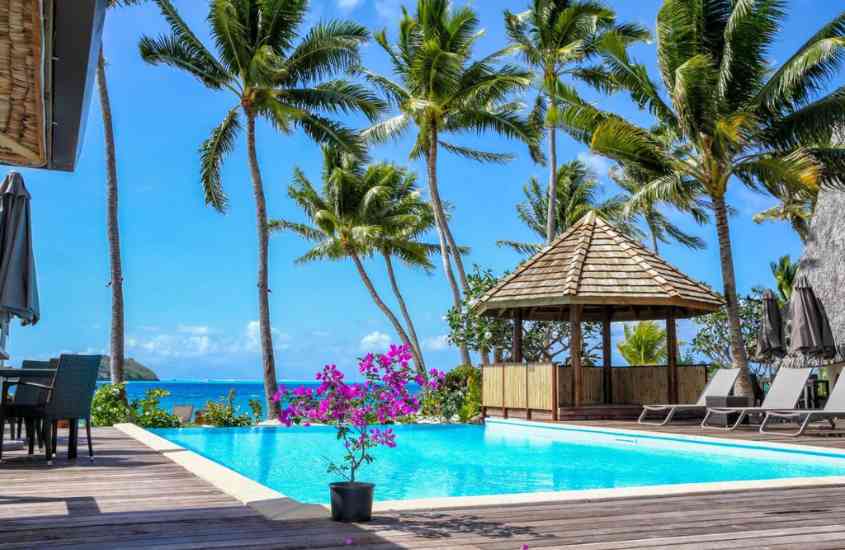 durante o dia, árvores, plantas e espreguiçadeiras em frente a piscina ao ar livre em área de lazer de um dos melhores hotéis na polinésia francesa
