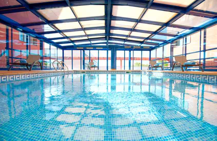 durante o dia, espreguiçadeira ao redor de piscina retangular em área de lazer coberta de um dos hotéis perto do aeroporto de barcelona