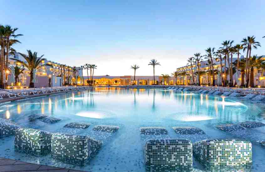 durante o dia, árvores ao redor de grande piscina redonda ao ar livre em um dos melhores hotéis em ibiza
