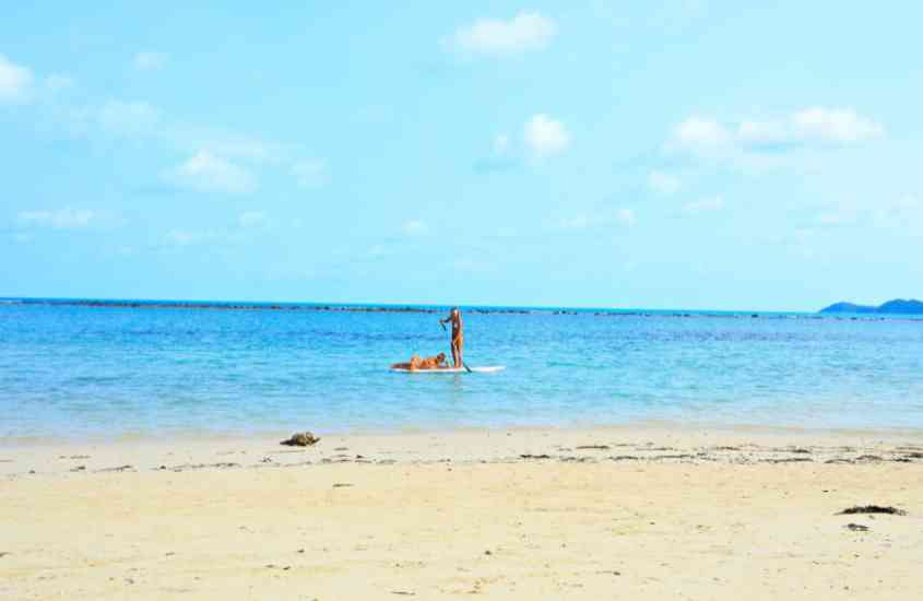 durante dia ensolarado, pessoa praticando stand up paddle em mar de koh samui