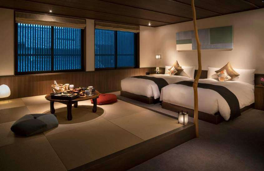 mesa de centro redonda e duas camas de casal em suíte de hotel em ryokan