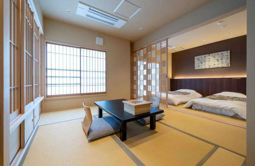 almofadas ao redor de mesa de madeira e dois colchões de casal em suíte de um ryokan em kyoto